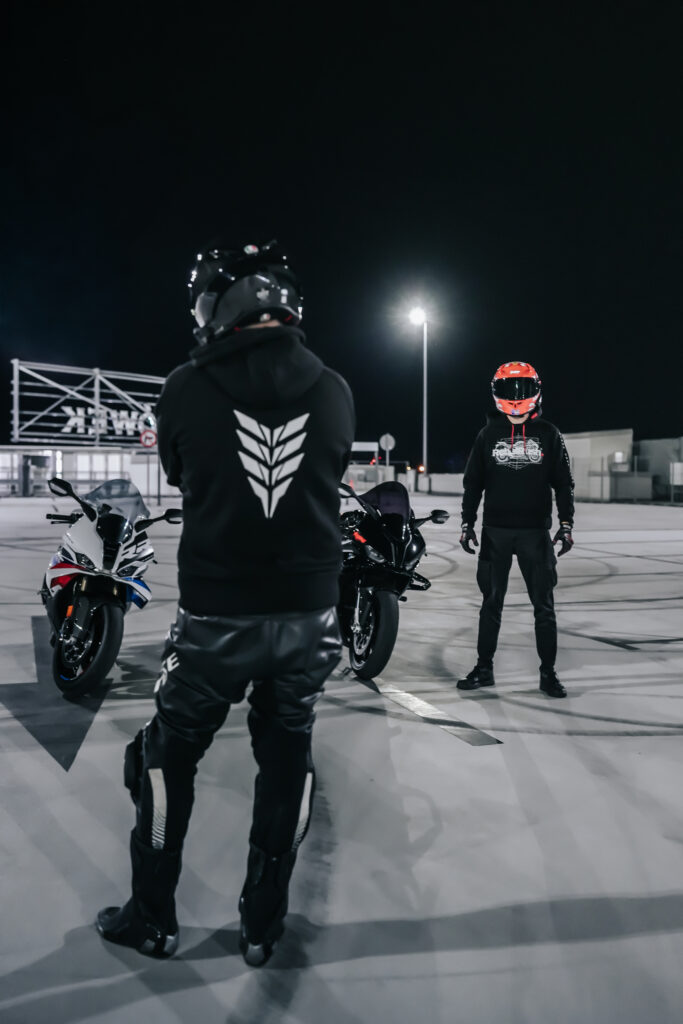 Dwóch motocyklistów nocą na dachu parkingu w bluzach RebelRush