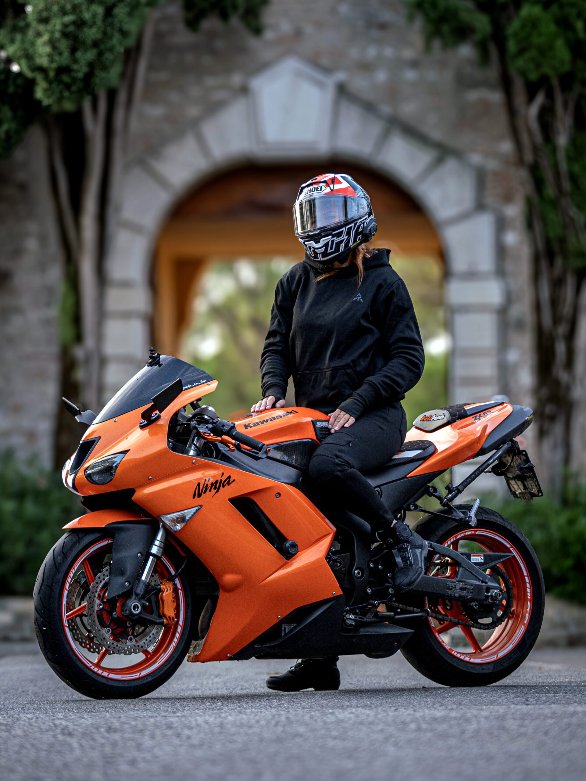 Motocyklistka w bluzie Ivy Burn na pomarańczowym motocyklu