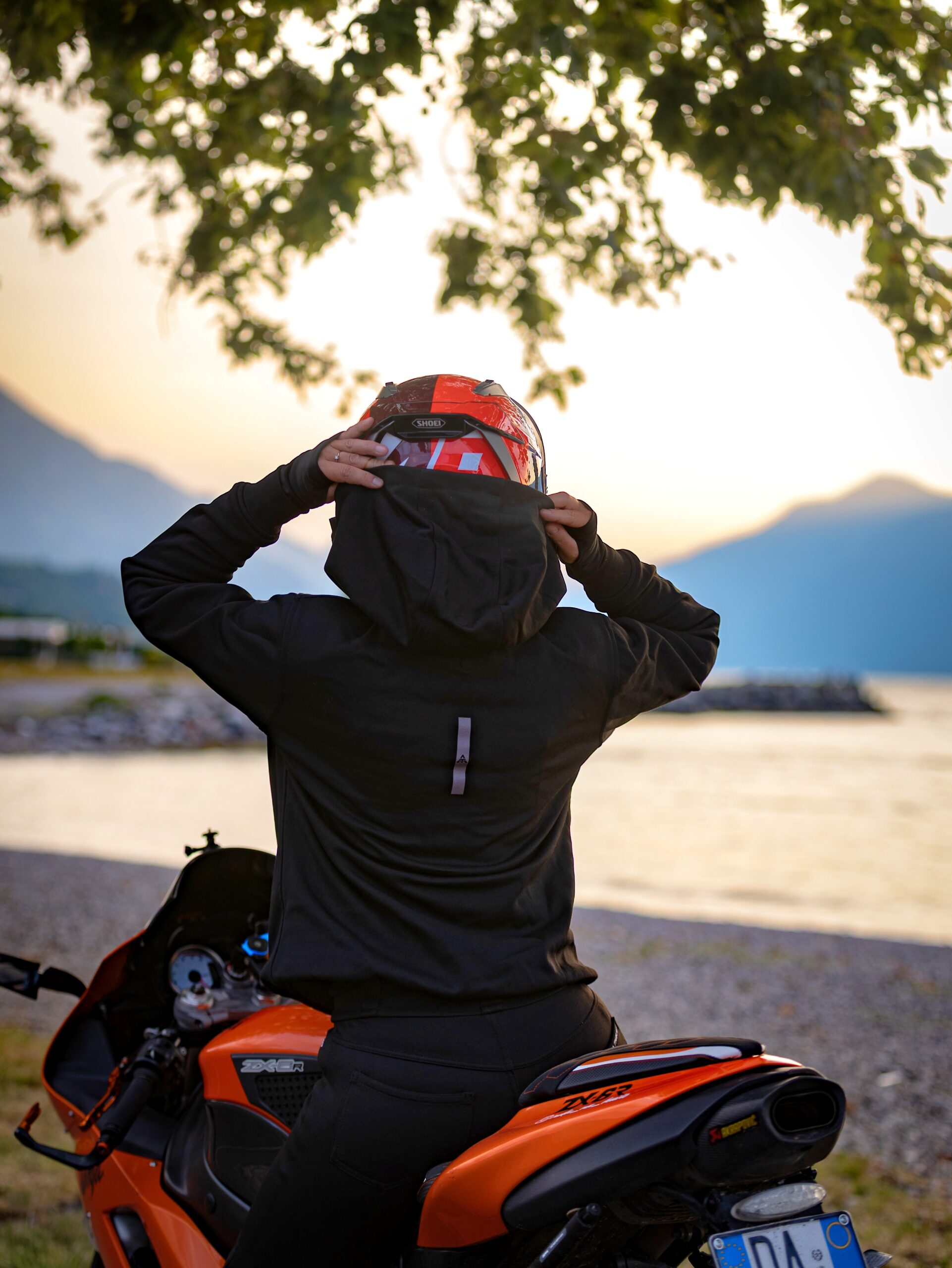 Ivy Burn od tyłu — motocyklistka zdejmuje kask nad jeziorem